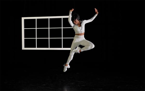 Dancer leaping in front of window frame