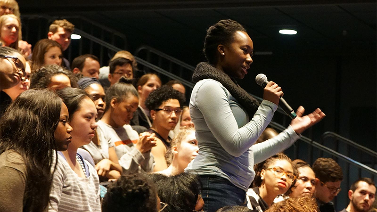 Woman asking question with microphone in hand, in audience