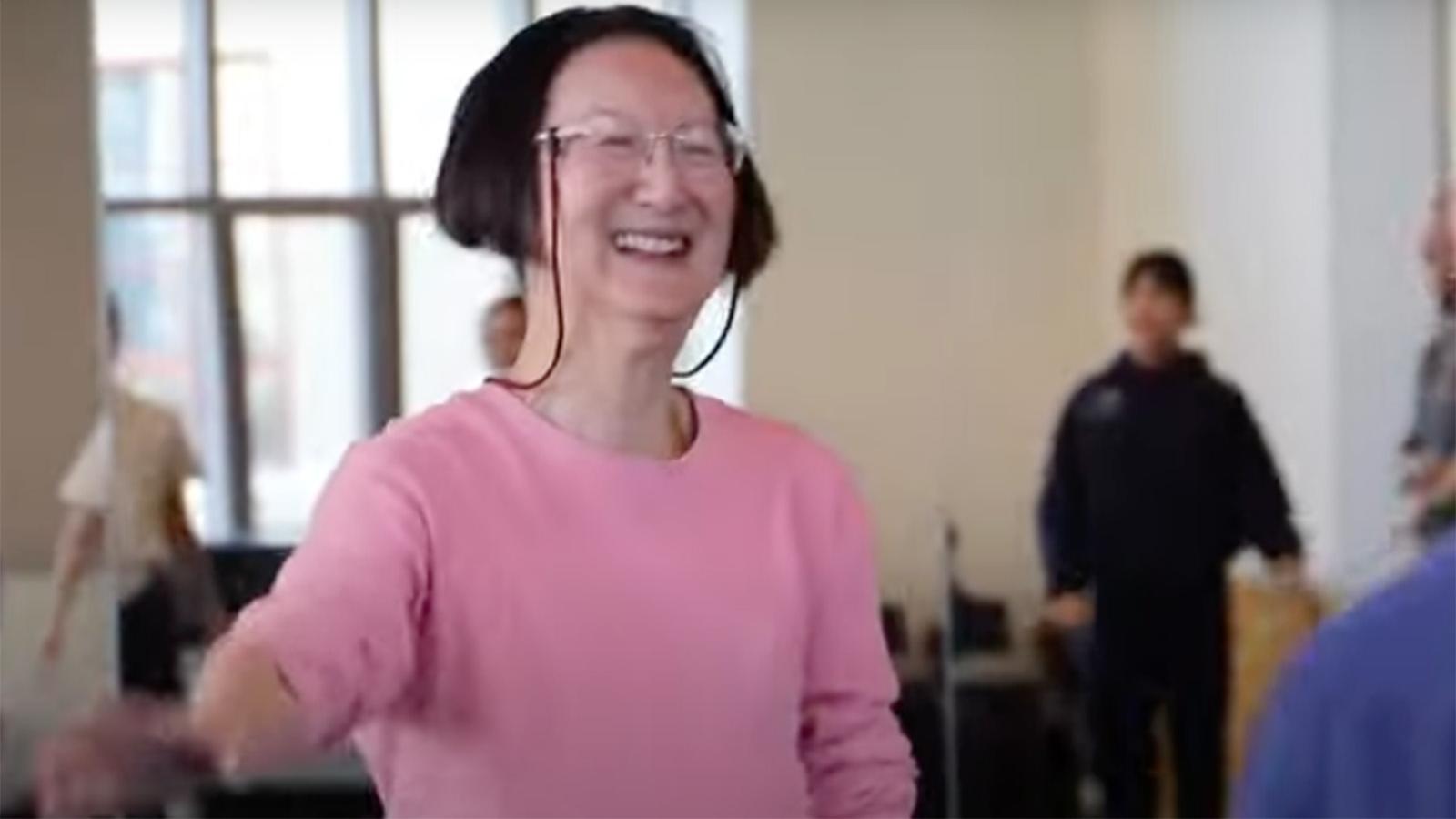 a person with short brown hair wearing glasses and a pink shirt