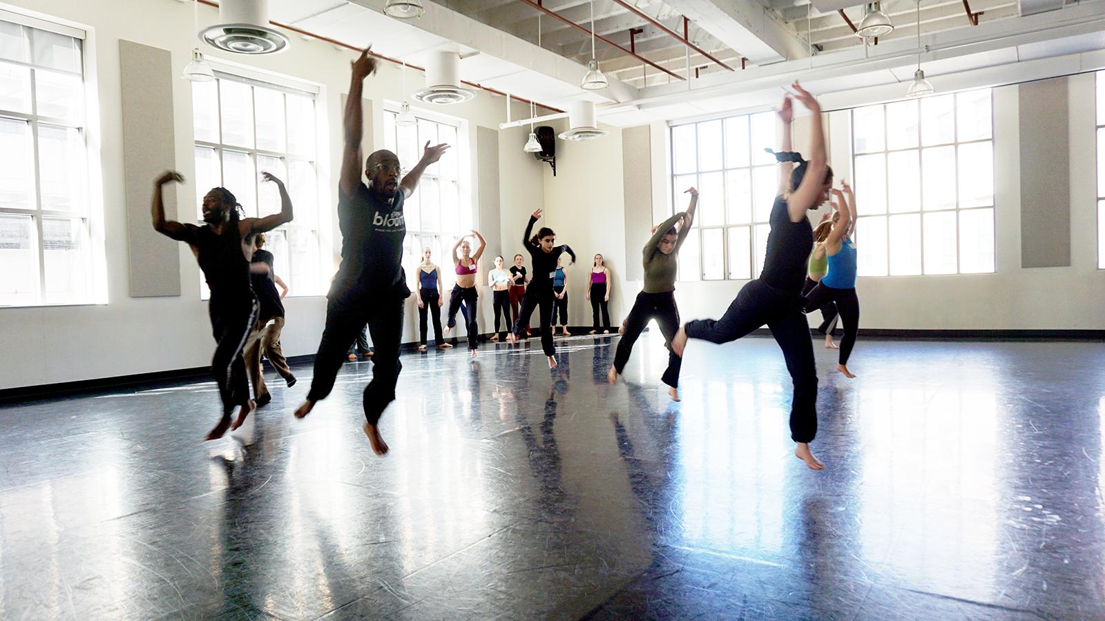 a group of dancers moving in a studio