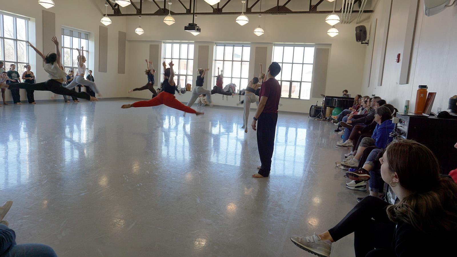 A group of dancers leaping in a studio