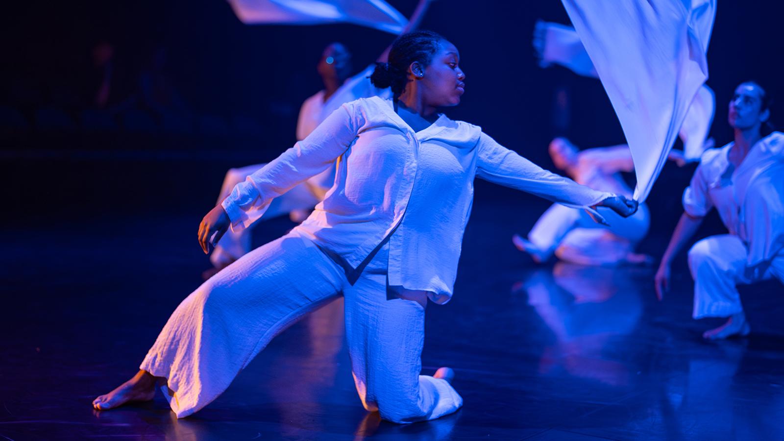 person kneeling in white costume and waiving white fabric