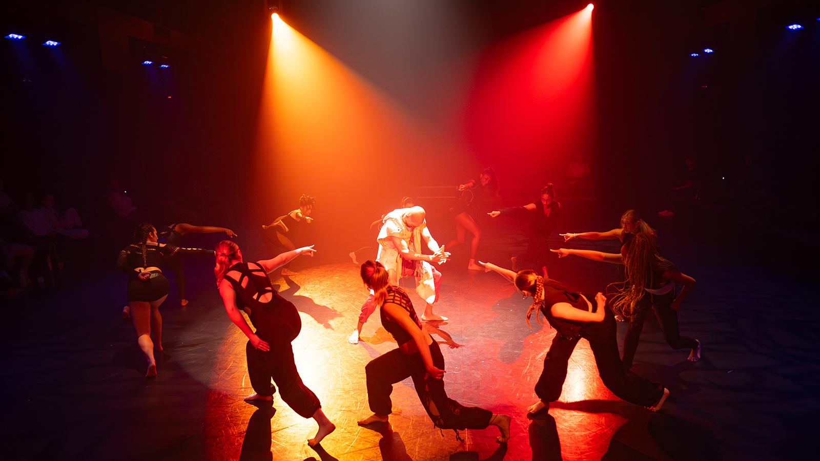 dancers wearing black on a lit stage